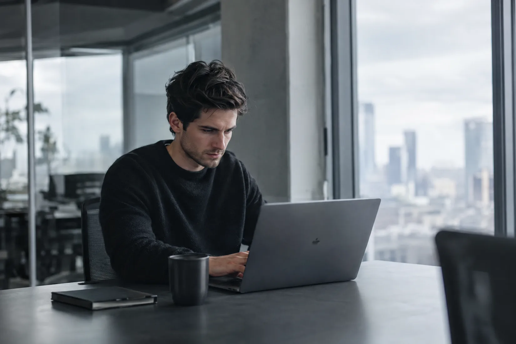 A founder at a laptop in a glass office